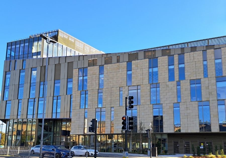 A glass and light fronted building against a blue sky
