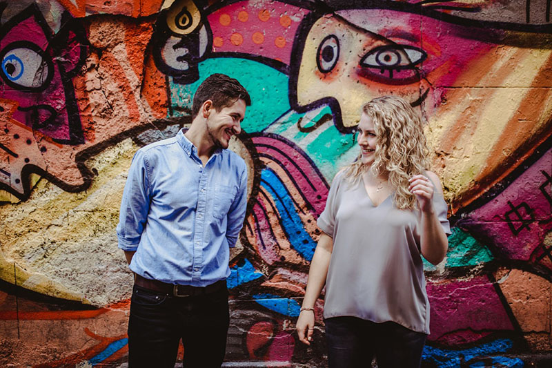 A man and a woman stood in front of a graffiti wall