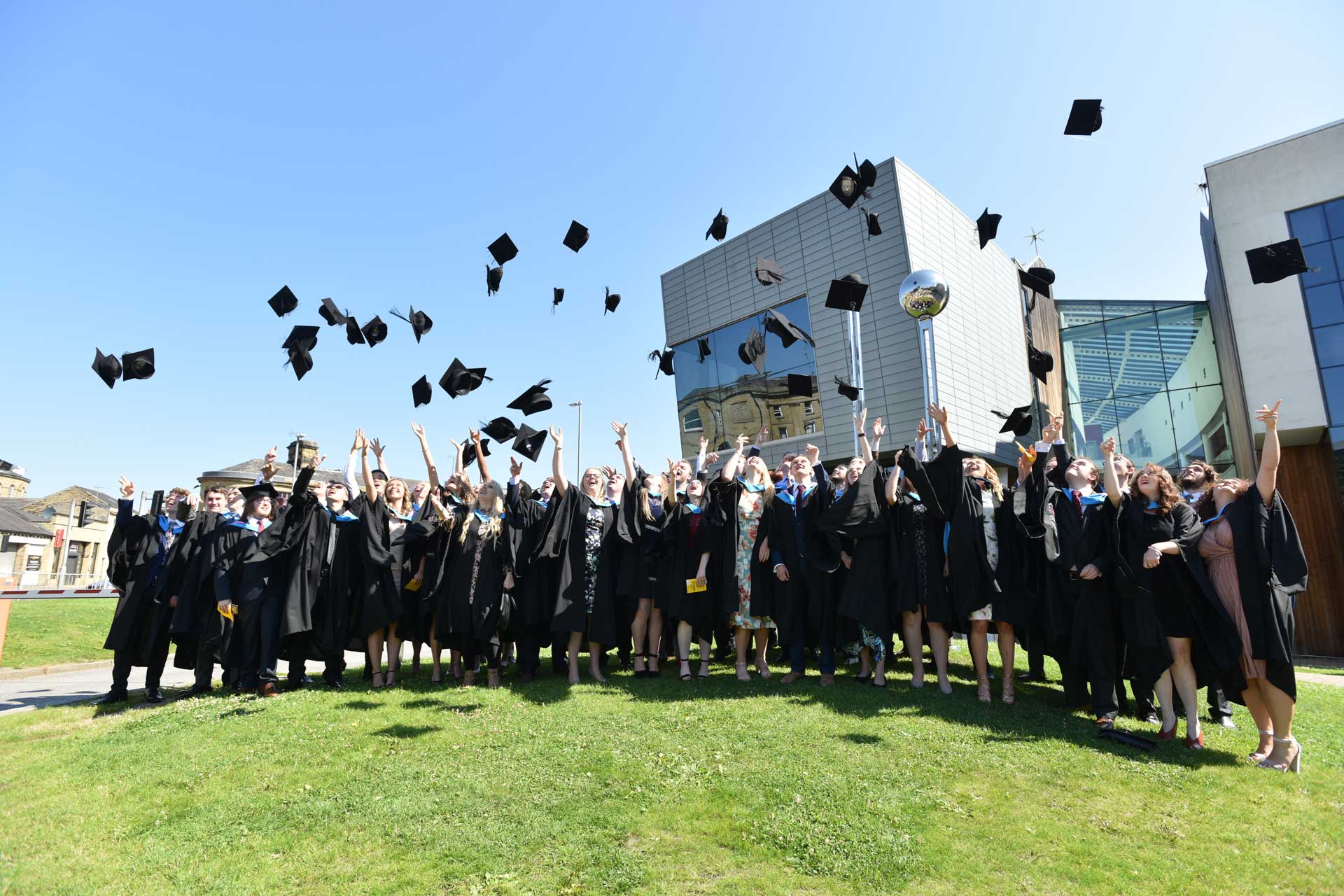 Graduates Throwing Mortar Boards infront of ADA Building