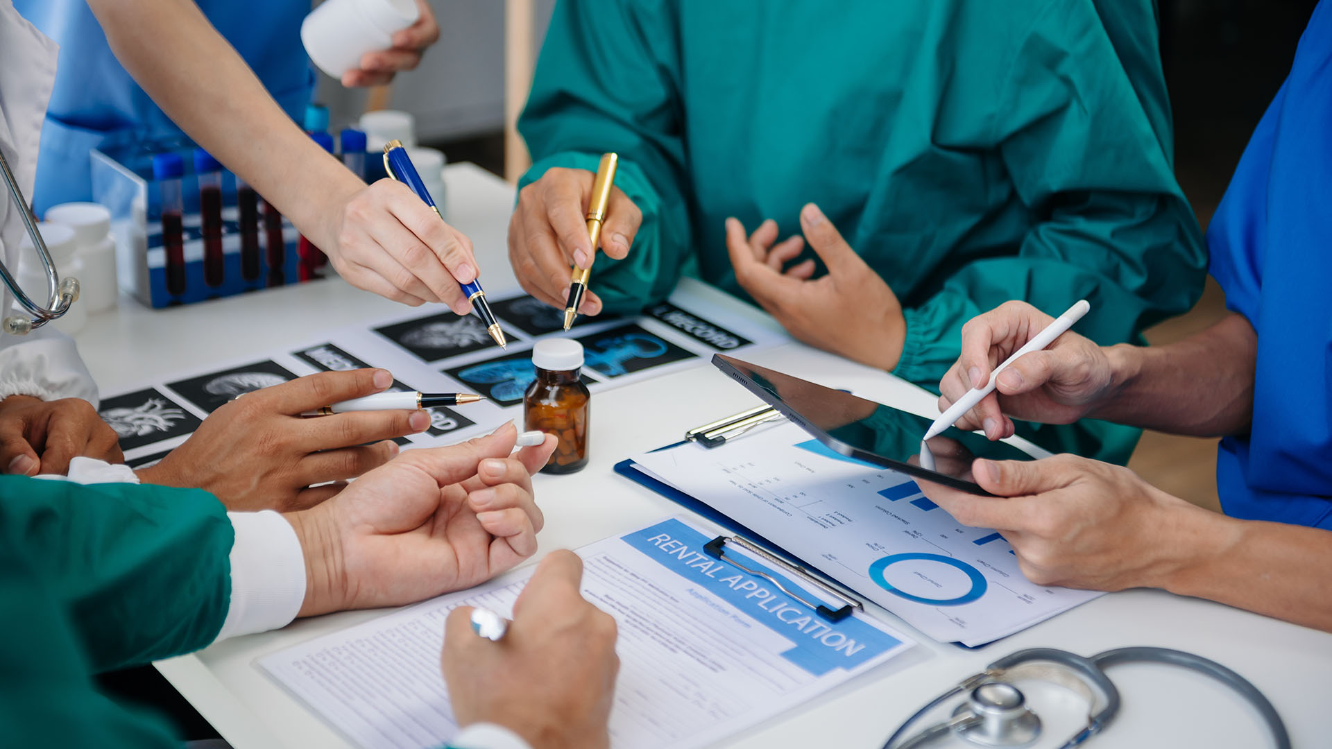 Medical professionals pointing pens at a jar of pills