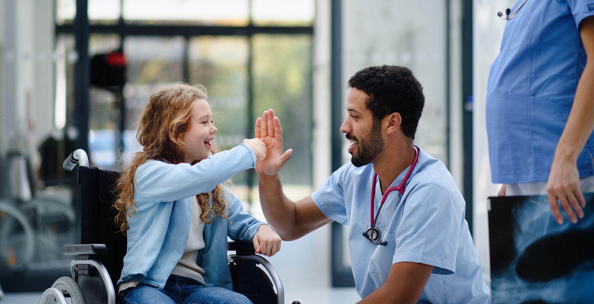 Male nurse trying to a high five a fist bump he is being given by a child
