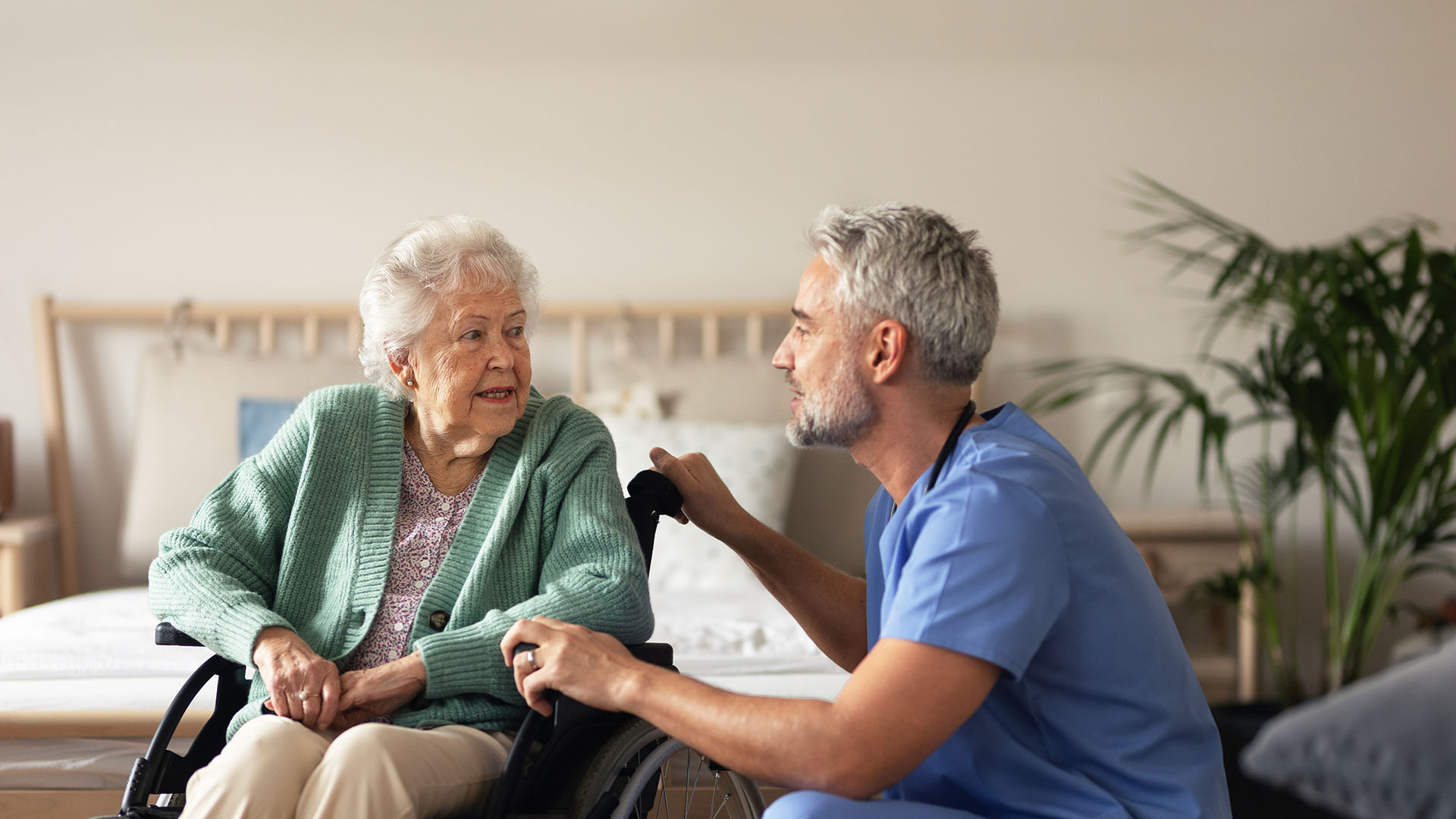 Male nurse talking to an old woman in wheelchair