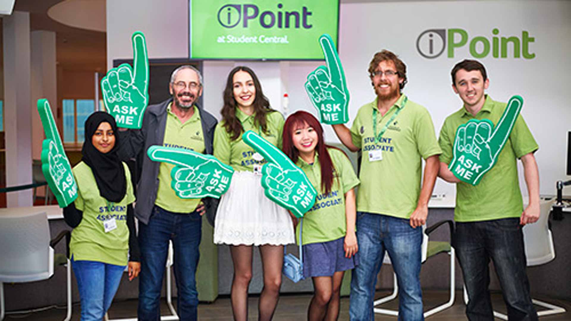 The iPoint desk in Student Central with its Customer Support Assistants holding 'Ask me' signs smiling.