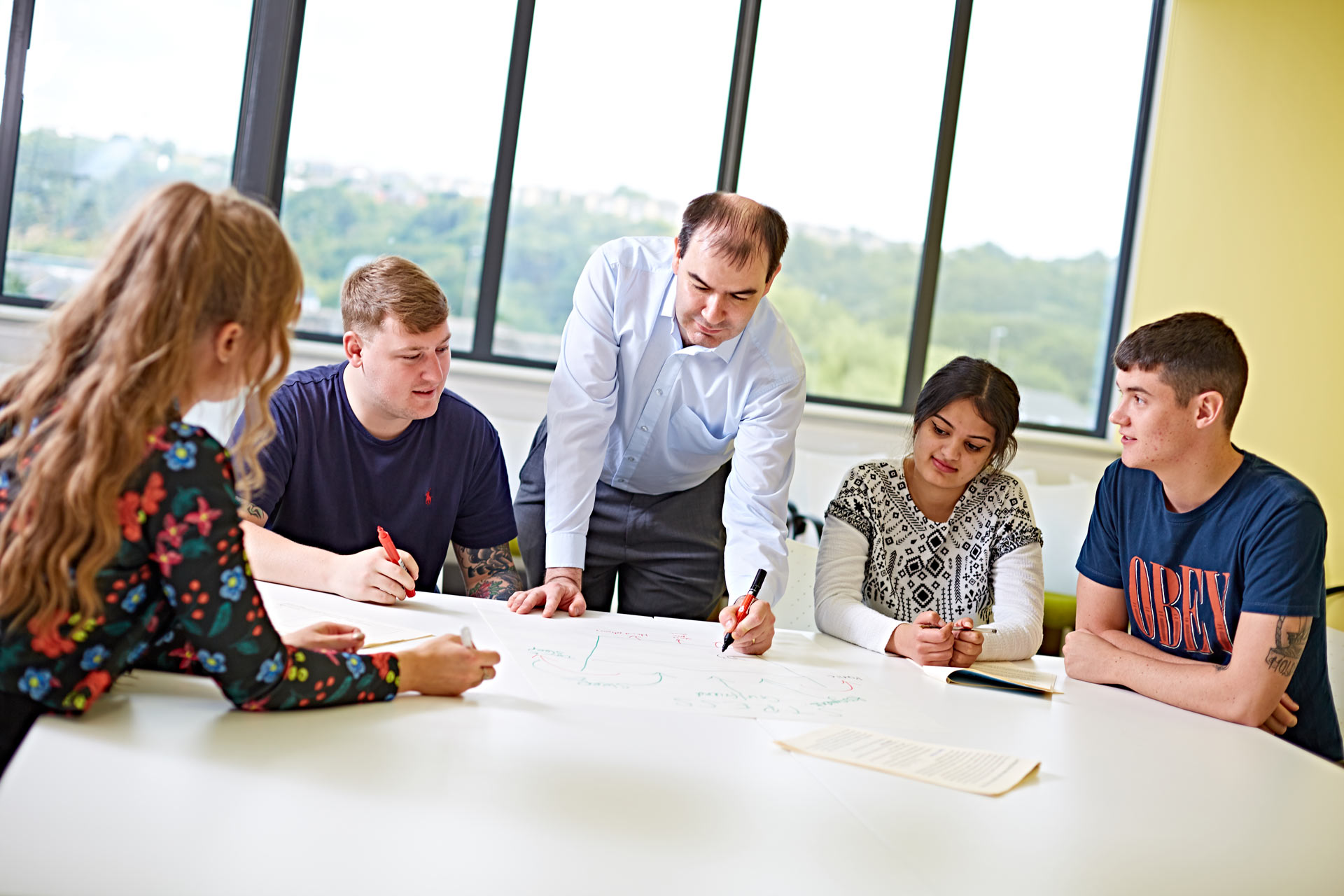 A group photo of staff and students working around a table